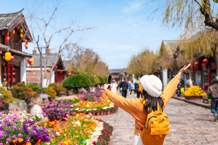 Mujer haciendo con gorro y abrigo haciendo turismo en Lijiang